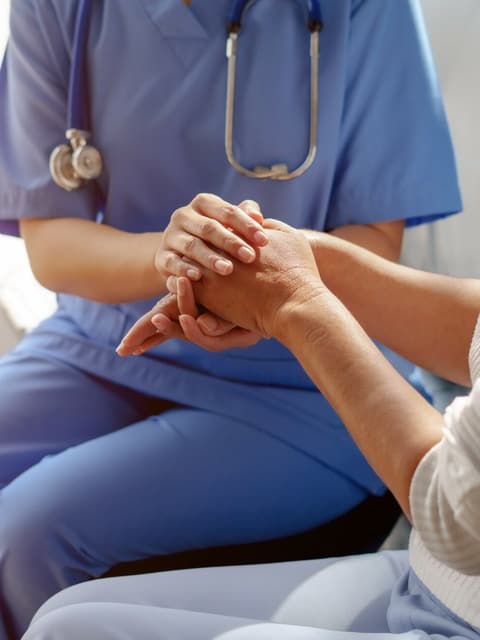 A clinician holding a patient's hands during a consultation